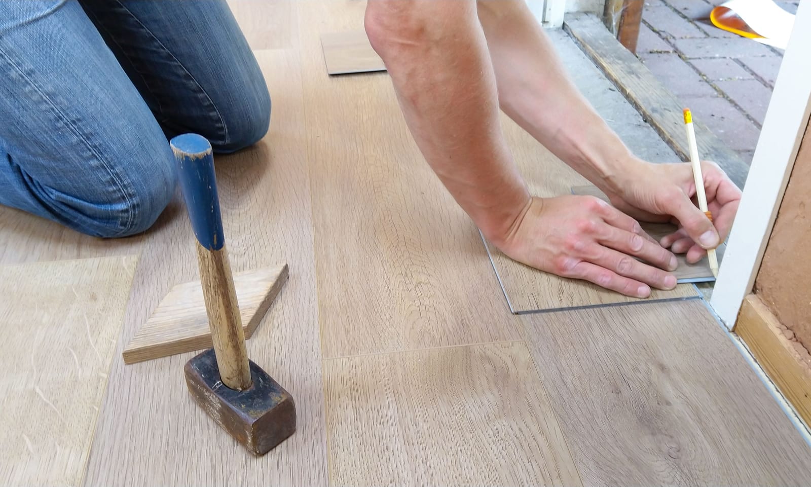 Installer laying laminate plank flooring during a Las Vegas installation