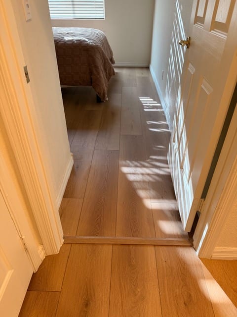 Finished wood-look flooring flowing through a Las Vegas hallway and bedroom